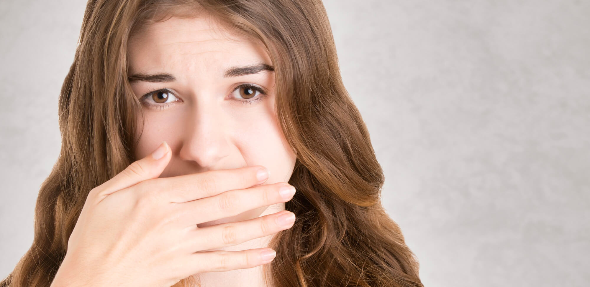 Worried young woman covering her mouth after swallowed braces bracket