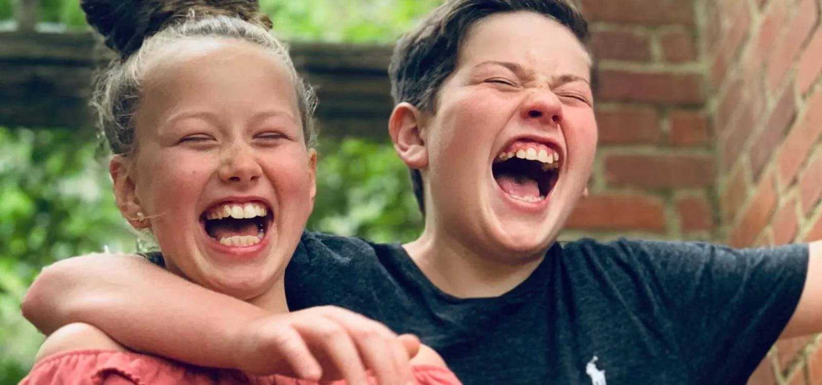 siblings hug and laugh about what causes crowded teeth