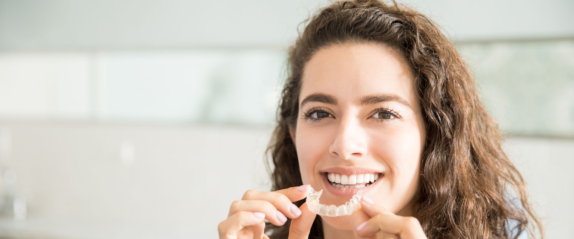 adult holds Invisalign tray and wonders "Can I use whitening toothpaste with Invisalign"