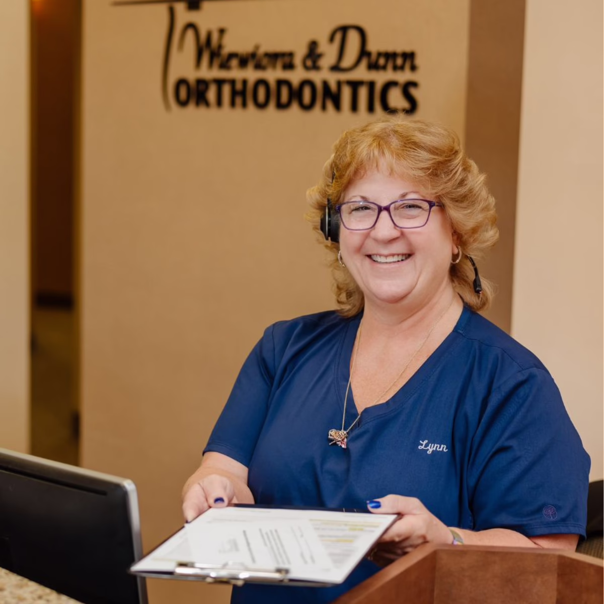 Front office desk handing paperwork, smiling, Wiewiora & Dunn Orthodontics